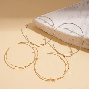 Irregular geometric hoop earrings in gold and silver finish on marble display
