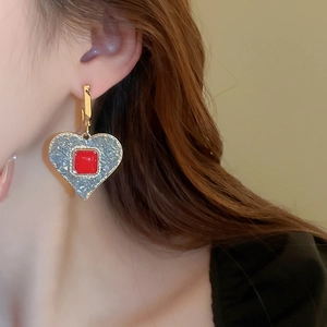 Detail of vintage heart earrings with red square crystal on model in golden finish