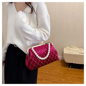 Detail of burgundy velvet crossbody bag with quilted patterns and pearl handle