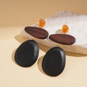 Detail of vintage teardrop earrings with amber resin beads and dark wood geometric pendants