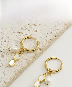 Detailed shot of 18K gold stainless steel hoop earring with pearl and shell pendants