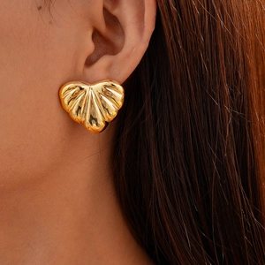 Close-up of golden acrylic heart earring with shell texture on model ear