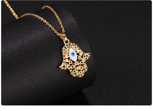 Macro shot of gold Hamsa Hand pendant with Evil Eye and colorful cubic zirconia inlay