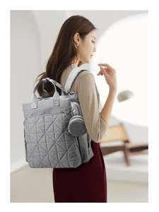 Detail view of grey quilted diaper backpack showing adjustable straps and coin pouch
