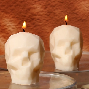 Faceted skull-shaped scented candle with geometric design and warm flickering flame