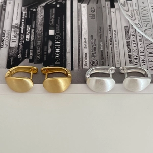 Detail of matte brushed gold and silver hoop earrings on a fashion magazine background