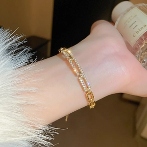 Close-up of gold geometric hollow bracelet with zircon inlay on a woman's wrist
