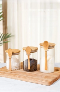 Three-piece borosilicate glass jars with bamboo lids and spoons on wooden board