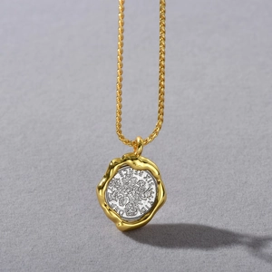 Macro detail of vintage 18k gold plated coin pendant with intricate silver relief
