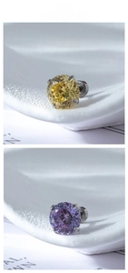 Macro shot of silver four-prong earrings with yellow and purple cubic zirconia stones