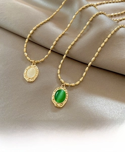 Detail view of vintage cat eye stone necklaces in emerald and milky white on satin