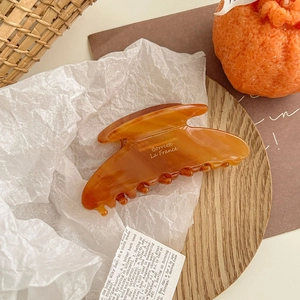 Detail view of large amber acetate shark hair claw clip on vintage background
