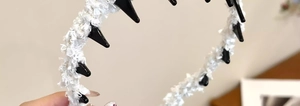 Détail d'un serre-tête en tweed blanc avec pointes punk noires et dents antidérapantes