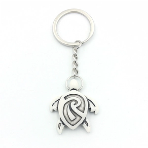 Silver metal sea turtle keychain with tribal spiral pattern on polished alloy shell