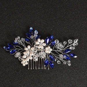 Detail of silver bridal hair comb with deep blue crystals and white pearls on black background