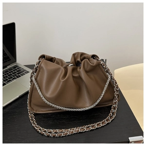 Detail of dark brown pleated cloud handbag with silver metal chain strap on desk