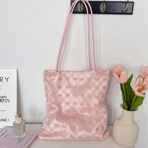 Close-up of pink quilted tote bag featuring satin finish and detailed bow patterns