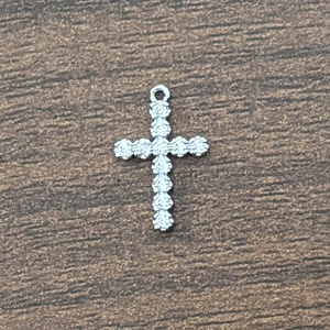 Macro view of silver cross pendant with granular relief and polished top ring