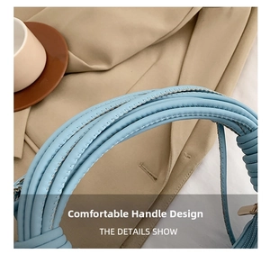 Close-up of the light blue woven leather handle and stitching on the minimalist shoulder bag