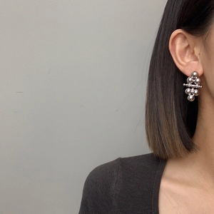 Close-up of dangling silver ball earrings worn by model for a minimalist jewelry look