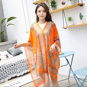 Close-up of orange silk scarf with intricate paisley patterns worn as a beach cover-up
