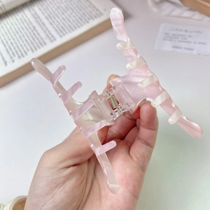 Detail of pink marble pattern hair claw clip with metallic spring and smooth finish