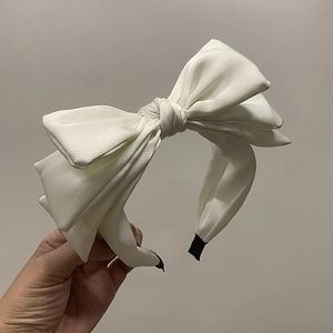 Detail of white satin triple-layered bow headband with black fabric tips