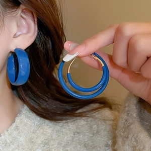 Close-up of Klein blue minimalist hoop earrings with smooth glossy finish on model