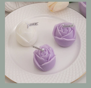 Top view of white and purple rose-shaped scented candles on a white ceramic plate