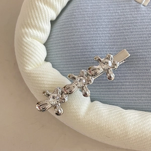 Macro view of silver-toned liquid metal hair clip featuring three sparkling rhinestones