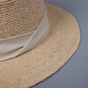 Gros plan sur la texture en raphia tissé main et ruban assorti du chapeau de soleil