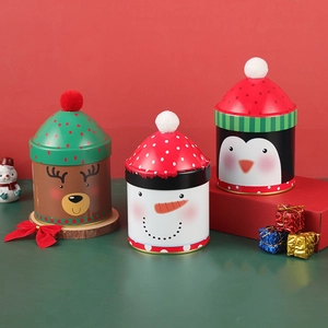 Three Christmas tin cans featuring reindeer and snowman designs on festive stands