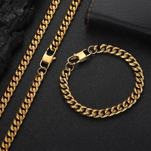 Flat lay of gold Cuban link necklace and bracelet set on a textured black background