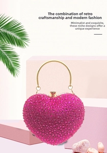 Close-up of heart-shaped rhinestone evening bag with rose red crystals and gold handle