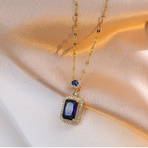 Detail of a golden necklace featuring a rectangular blue crystal pendant on gold silk