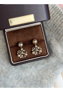 Close-up of champagne pearl and crystal flower earrings in a premium jewelry box