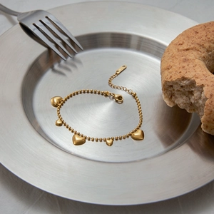 Elegant 18k gold plated stainless steel heart charm bracelet on a decorative plate