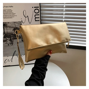 Dettaglio di una pochette dorata metallizzata con design pieghevole e cinturino da polso