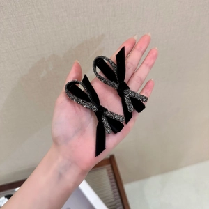 Detail of hand-held black velvet hair clips with sparkling rhinestone bow accents