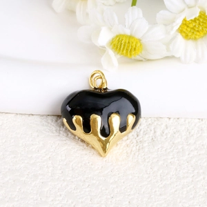 Macro shot of a melting black and gold heart enamel pendant with a drip design