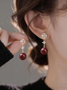 Detailed shot of 18K gold flower stud earrings with red beads and sparkling zircons