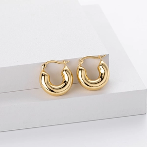 Chunky S925 sterling silver hoop earrings in polished gold finish on white podium