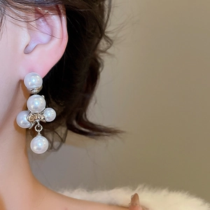 Dettaglio di eleganti orecchini pendenti con perle in argento indossati da una modella