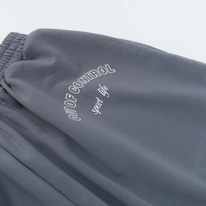 Détail du tissu en maille gris foncé et du lettrage blanc imprimé à la taille du pantalon