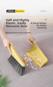 Close-up of soft mustard yellow mini broom and dustpan set cleaning desk crumbs