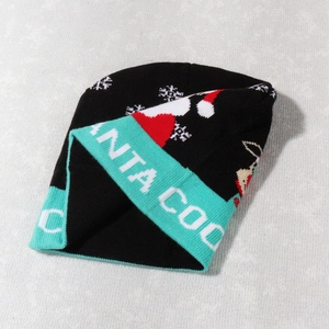 Close-up of knit Christmas beanie featuring Santa Cool text and snowflake patterns
