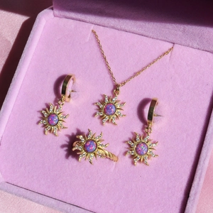 Golden sunburst jewelry set with purple opal stones in a pink velvet display box