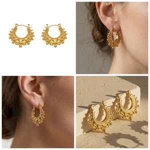 Detail of vintage bohemian gold horseshoe earrings with matte texture on model