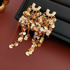 Vue détaillée de boucles d'oreilles dorées en U avec paillettes métalliques sur un coffret