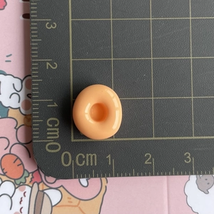 Mini orange resin donut accessory shown with a ruler for 1cm size measurement